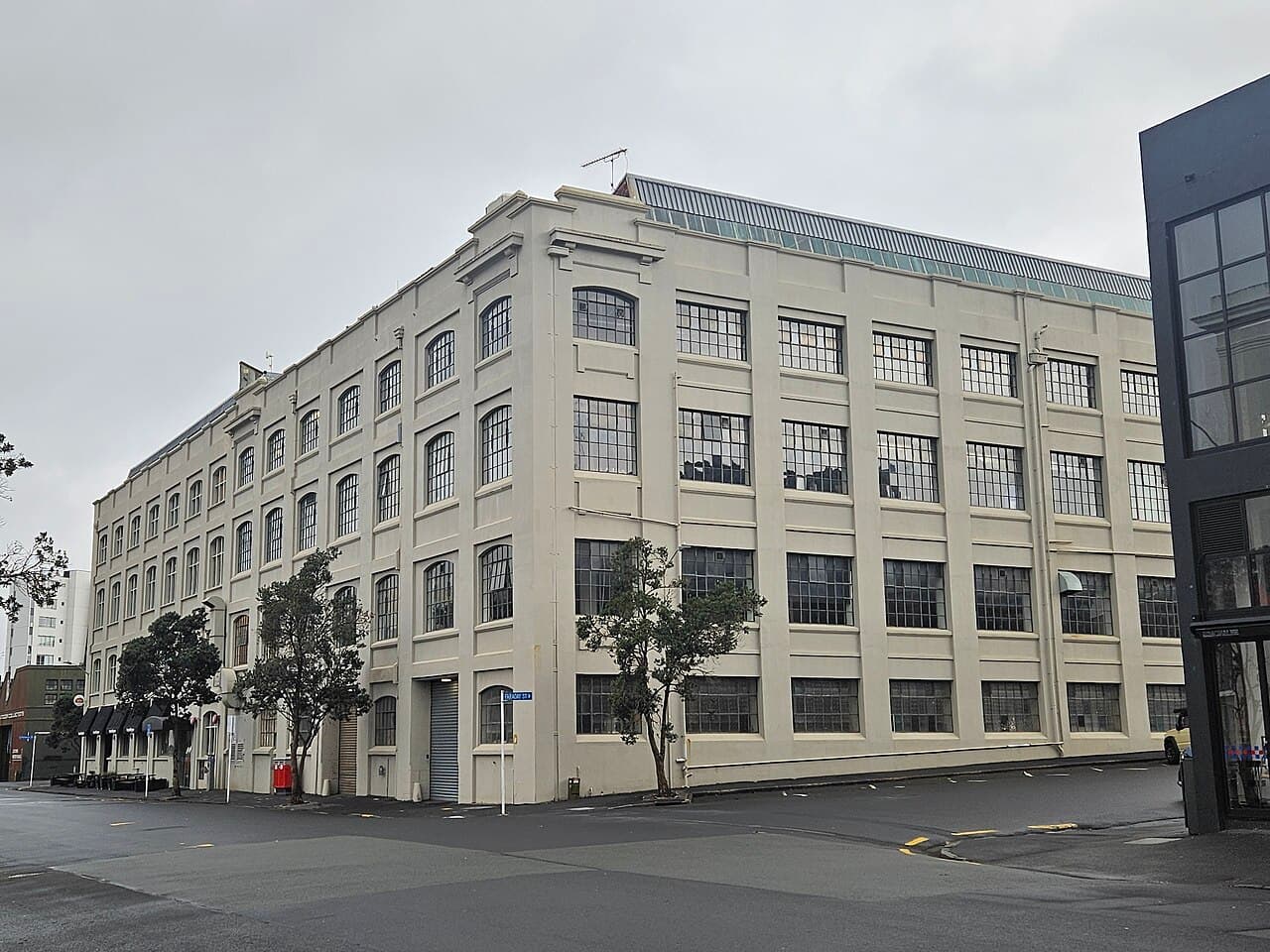 The former premises of the North Auckland Farmers' Co-operative and the Farmers' Cooperative Auctioneering Company at Parnell, Auckland, New Zealand — a large cream-rendered early-20th-century warehouse building with tall multi-pane windows wrapping the street corner